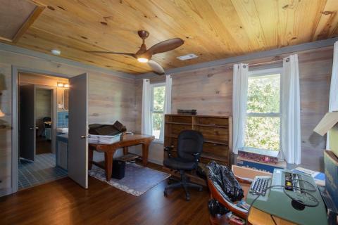 This bedroom is being used as an office with refinished original hardwood floors and many windows