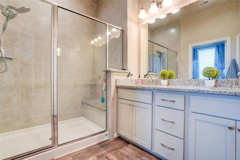 The gorgeous primary bathroom showcases a walk-in closet, a granite vanity, dual undermount sinks, and a walk-in shower with a built-in bench seat and floor to ceiling tile!