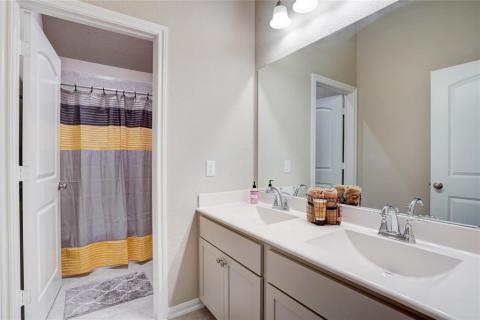 The second floor bathroom features dual sinks, tile flooring and a tiled tub and shower combo.