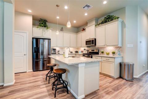 The kitchen is equipped with under-cabinet lighting, granite countertops, herringbone-tiled backsplash, and stainless steel appliances.