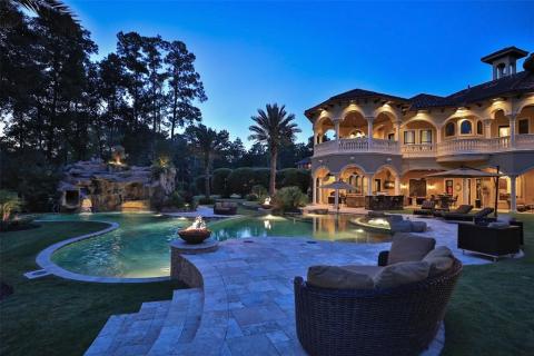 Breathtaking view of a sunset shot of the back of the house and the main pool with fire bowls, the swim up rock cave, water falls & fabulous landscape lighting! Relaxation is key in this backyard! Breathtaking view of a sunset shot of the back of the house and the main pool with fire bowls, the swim up rock cave, water falls & fabulous landscape lighting! Relaxation is key in this backyard!