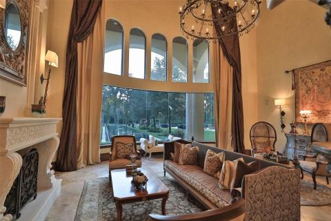 Huge living room with a wall of windows that looks out to the beautiful reflection pool and the gorgeous back yard. Decorative stone fireplace, travertine floors, exquisite chandelier is featured. Rich designs throughout this incredible home! Huge living room with a wall of windows that looks out to the beautiful reflection pool and the gorgeous back yard. Decorative stone fireplace, travertine floors, exquisite chandelier is featured. Rich designs throughout this incredible home!