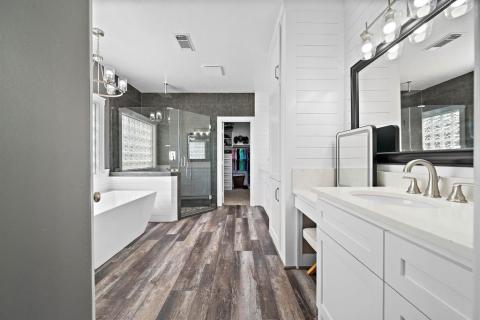 The gorgeous Luxury floors continue into the bathroom en-suite from the Primary bedroom. Free standing tub, walk in shower with rain head, and Dual sinks with a Seated vanity section with lots of shiplap accenting this Exquisite bathroom
