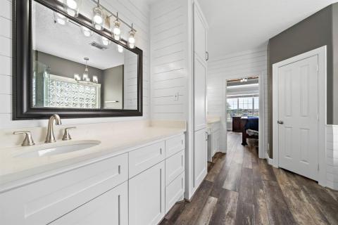 View of this enormous en-suite from the walk in closet area that helps high light all the counter space and cabinetry.
