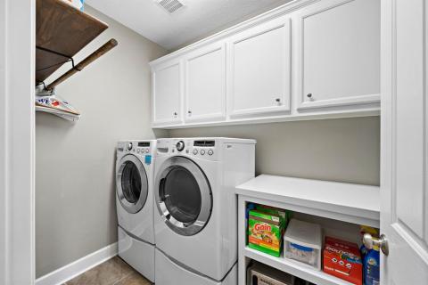 A Walk in Laundry room with a cabinetry, a folding area, and hanging rack.