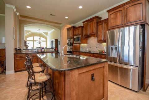 Gourmet kitchens also qualify for spectacular "furnishings"! Wood finishes, in any setting, instantly imply a warm, courtly envirnoment. This rich, aged-look cabinetry completely agrees with deep colored granite counters and earth-toned tile backsplash. This gorgeous, oversized center island offers an extended counter, suitable for your favorite stools. (You don't have to look far for them, however, because the bar stools are included in the home!)
