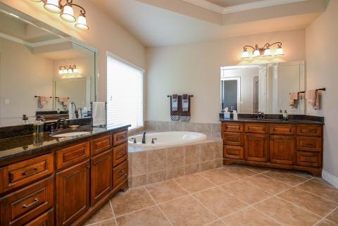 A little bit of an aged-style, rustic vibe completely agrees with the placement of dual/separate sinks/vanities/storage.  Bright, restful walls and gorgeous tile flooring, embrace vanity pieces and lush garden tub.