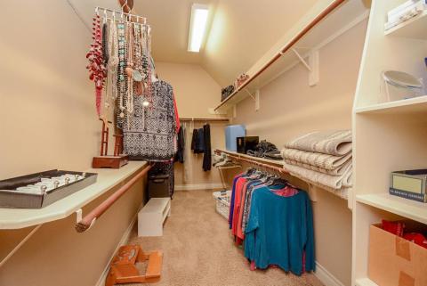 No, this is not a private shopping aisle in a department store. It is your own carpeted primary walk-in closet to store and organize everything you own in one space!