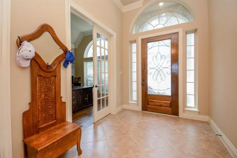 High ceilings and classic, sophisticated crown molding embraces the wide entry foyer. At left, beyond traditional french doors, is the perfect spot for your study/home office.