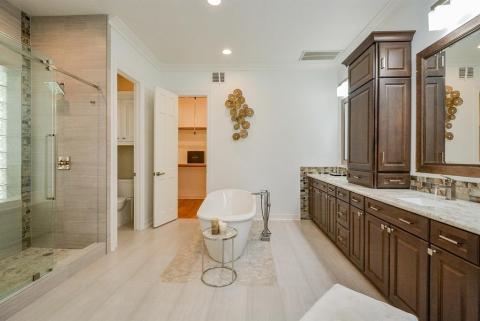 The oversized walk in, glass enclosed shower (with glass block window) has a prime view of the focal, freestanding, oval soaking tub in this marvelously updated ensuite bath.The space also includes 2 enormous his/her closets with 3-tiered hanging racks.