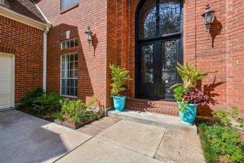 This is how exterior luxury warmly welcomes guests. Palatial, 2-story iron Contera double doors sit under the covered, high arched, red brick lined entry.