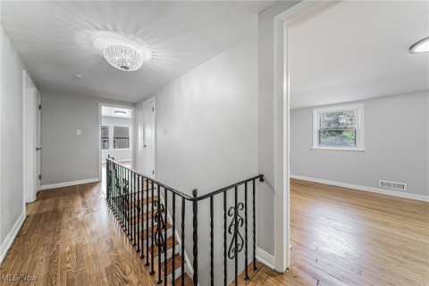 Corridor featuring an inviting chandelier and hardwood flooring