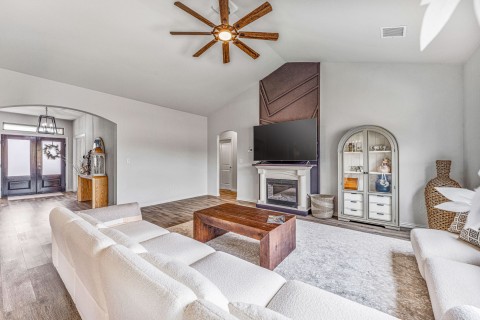 Living room with hardwood / wood-style floors, high vaulted ceiling, and ceiling fan