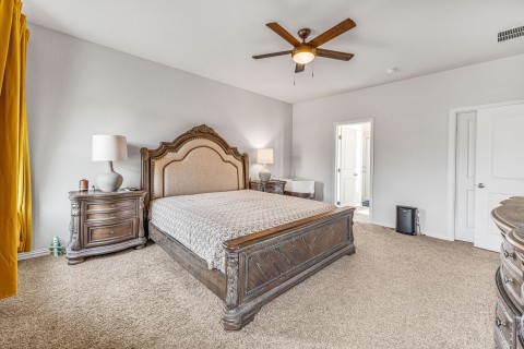 Bedroom with ceiling fan and light carpet