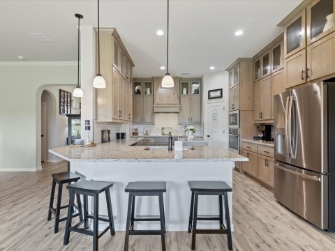 Kitchen with a sink, stainless steel fridge with ice dispenser, custom range hood, a peninsula