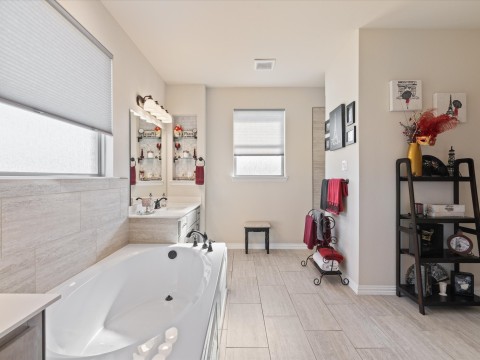 Bathroom with a healthy amount of sunlight, a garden tub, vanity, and visible vents