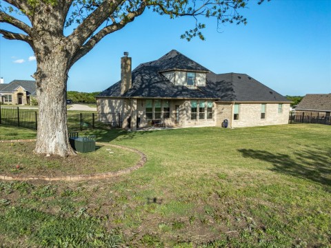 Back of property featuring a lawn and metal fenced backyard