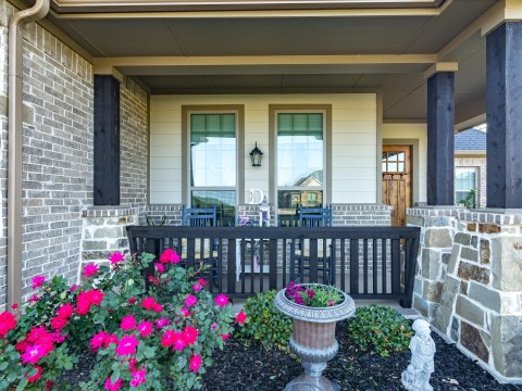 View of exterior entry featuring brick siding and a porch
