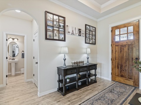 Entrance foyer with light wood-style flooring, baseboards, arched walkways to access half bath