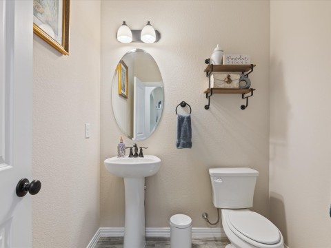 Half bath featuring baseboards, a sink, and toilet
