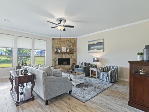 Living area with visible vents, baseboards, a ceiling fan, a fireplace, and crown molding