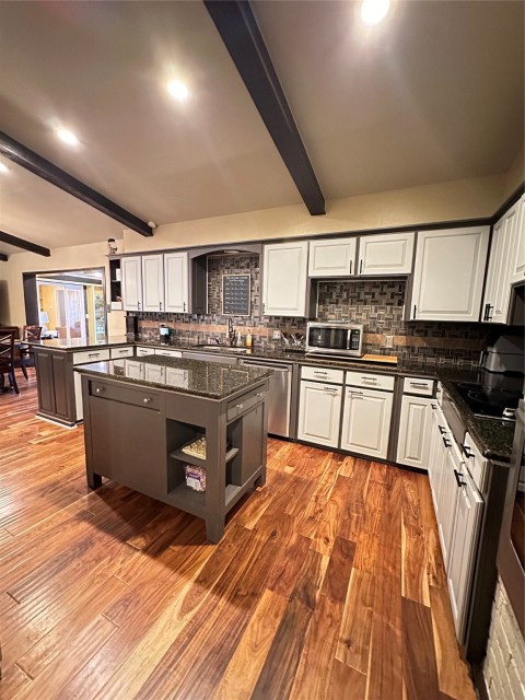Kitchen featuring white cabinets, beam ceiling, and hardwood / wood-style flooring