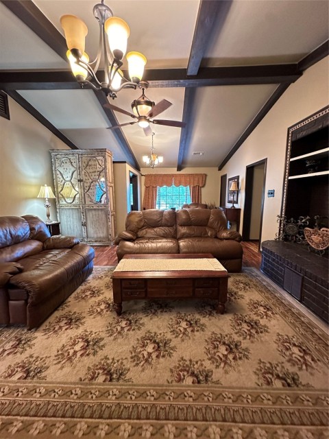Living room featuring hardwood / wood-style floors, lofted ceiling with beams, and a chandelier