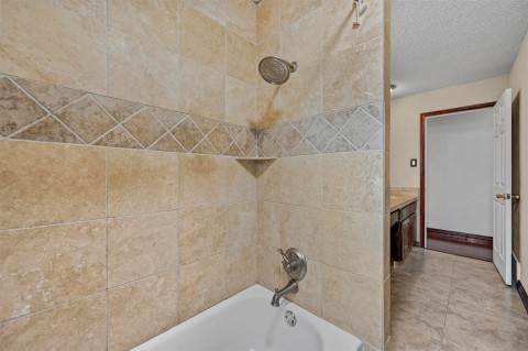 Bathroom featuring tiled shower / bath, tile flooring, and vanity
