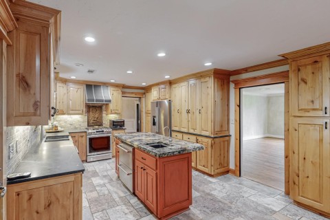 Kitchen showing SS Kitchaide appliances, under cabinet lighting, antique fireback behind stove with large Coppersmith vent hood.