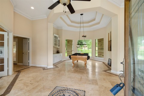 This spacious foyer features tile flooring, crown molding, and a high ceiling with a ceiling fan.