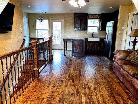 Kitchen with a textured wall, dark wood-style flooring, freestanding refrigerator, light countertops, and open floor plan