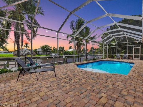 Pool at dusk featuring screened enclosure and a patio area