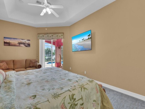 Bedroom featuring carpet floors, ceiling fan, a raised ceiling, and access to exterior