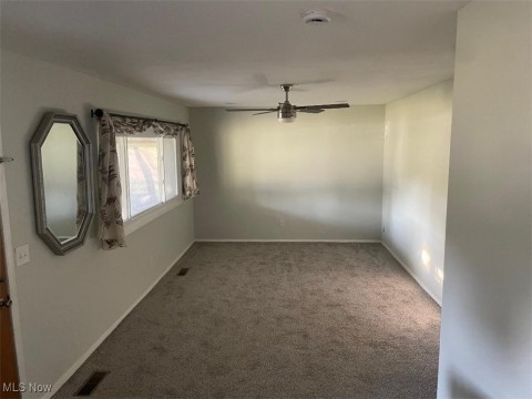 Empty room with carpet flooring, a ceiling fan, and a smoke detector