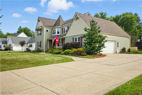 View of front of home with a front yard, driveway, a shingled roof, and a garage