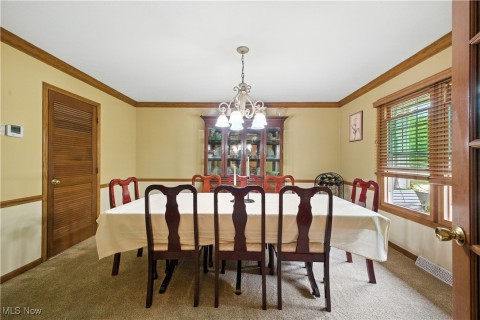 Carpeted dining area with crown molding and a chandelier