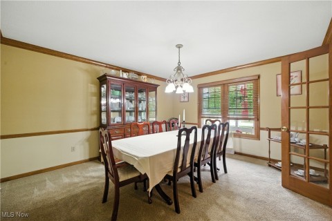 Dining area featuring light carpet, ornamental molding, and a chandelier