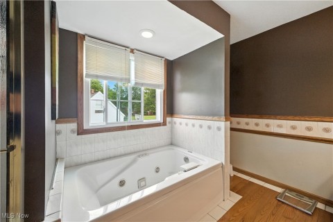 Full bath featuring a whirlpool tub and light wood-style floors