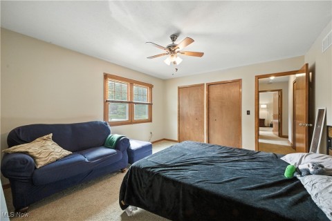 Bedroom featuring multiple closets, light carpet, and a ceiling fan