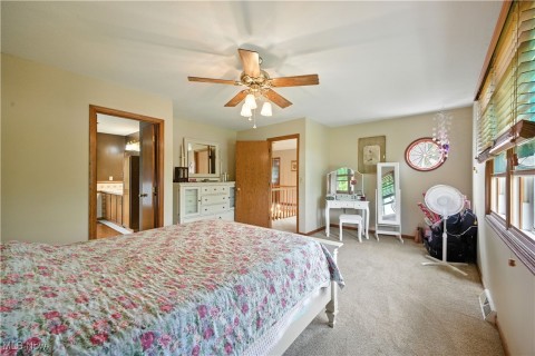 Bedroom featuring light carpet, ceiling fan, and ensuite bathroom