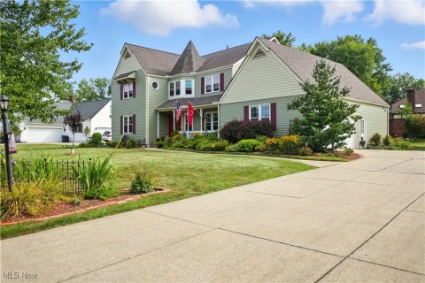 Victorian home featuring a front yard, concrete driveway, roof with shingles, and an attached garage