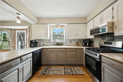 Kitchen featuring stainless steel appliances, gray cabinetry, decorative backsplash, light wood finished floors, and light countertops