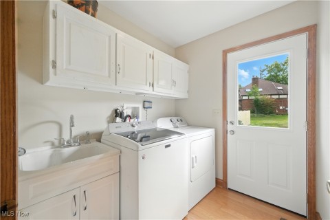 Laundry room featuring cabinet space, light wood-style flooring, and separate washer and dryer
