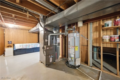 Unfinished basement with wood walls, water heater, and heating unit