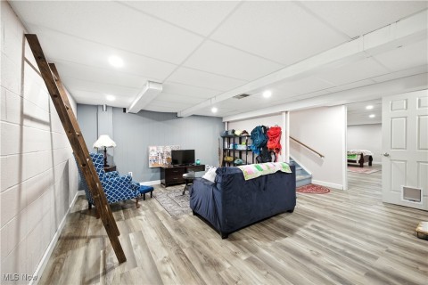 Living room featuring stairs, a paneled ceiling, light wood-style flooring, and recessed lighting