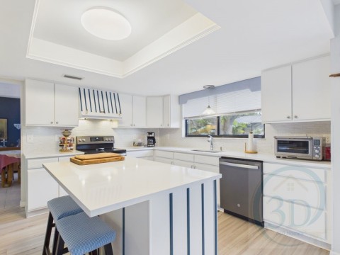 Kitchen with white cabinetry, a raised ceiling, stainless steel appliances, and light wood finished floors