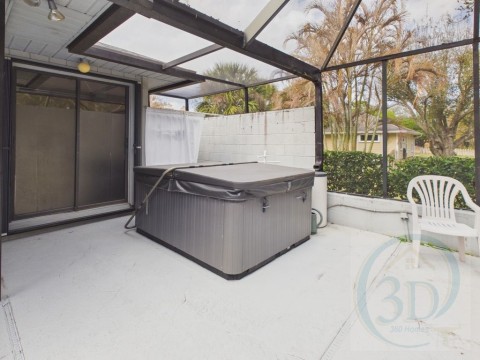 View of patio with a hot tub and a lanai