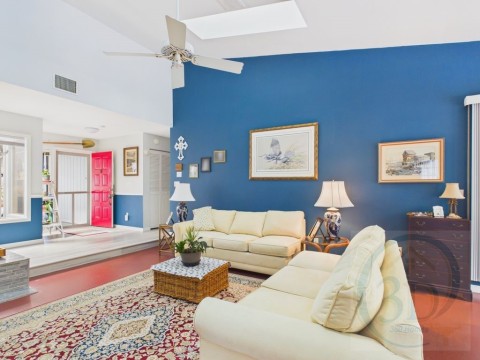Living area featuring lofted ceiling, ceiling fan, wood finished floors, and a skylight