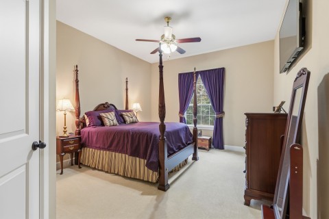 One of the secondary bedrooms that features carpet, a ceiling fan, great closet space, and an ensuite bathroom.