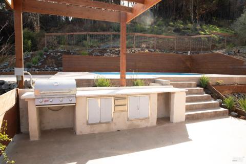 Outdoor kitchen set up within the pergola.